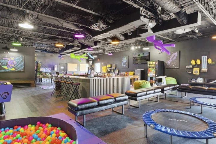 Modern play area with trampolines, ball pit, seating, and colorful decor in an indoor space.