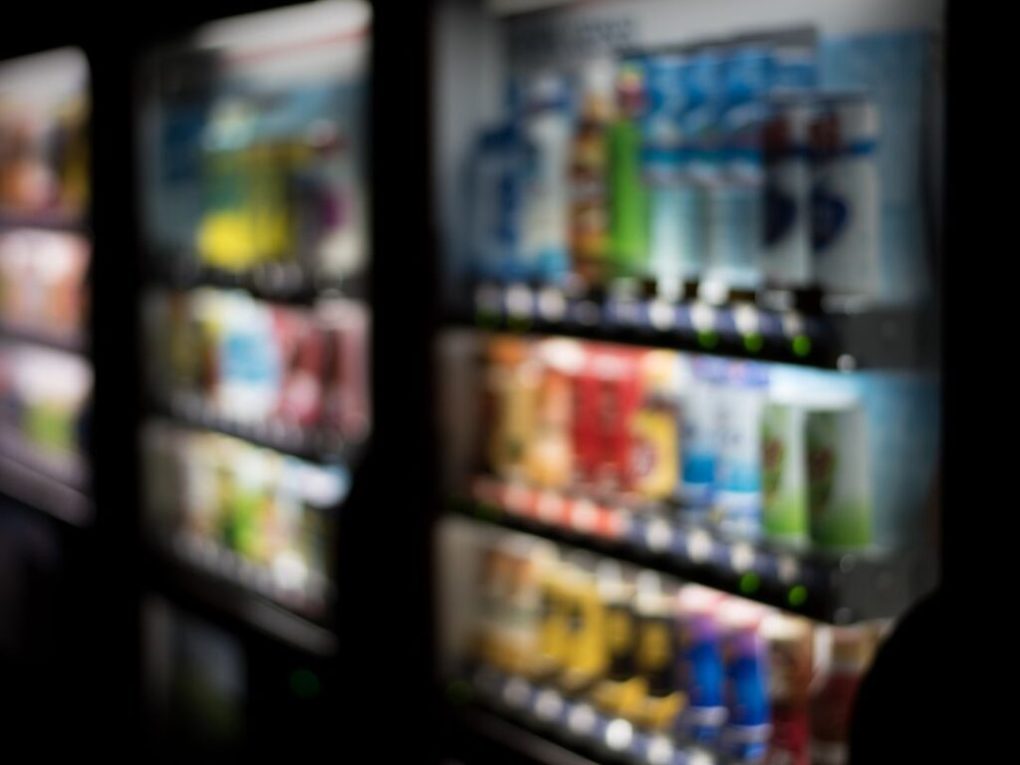 Where-Brevard-Comes-to-Play-28-1024×1024 Blurred image of vending machines with various drinks and snacks.