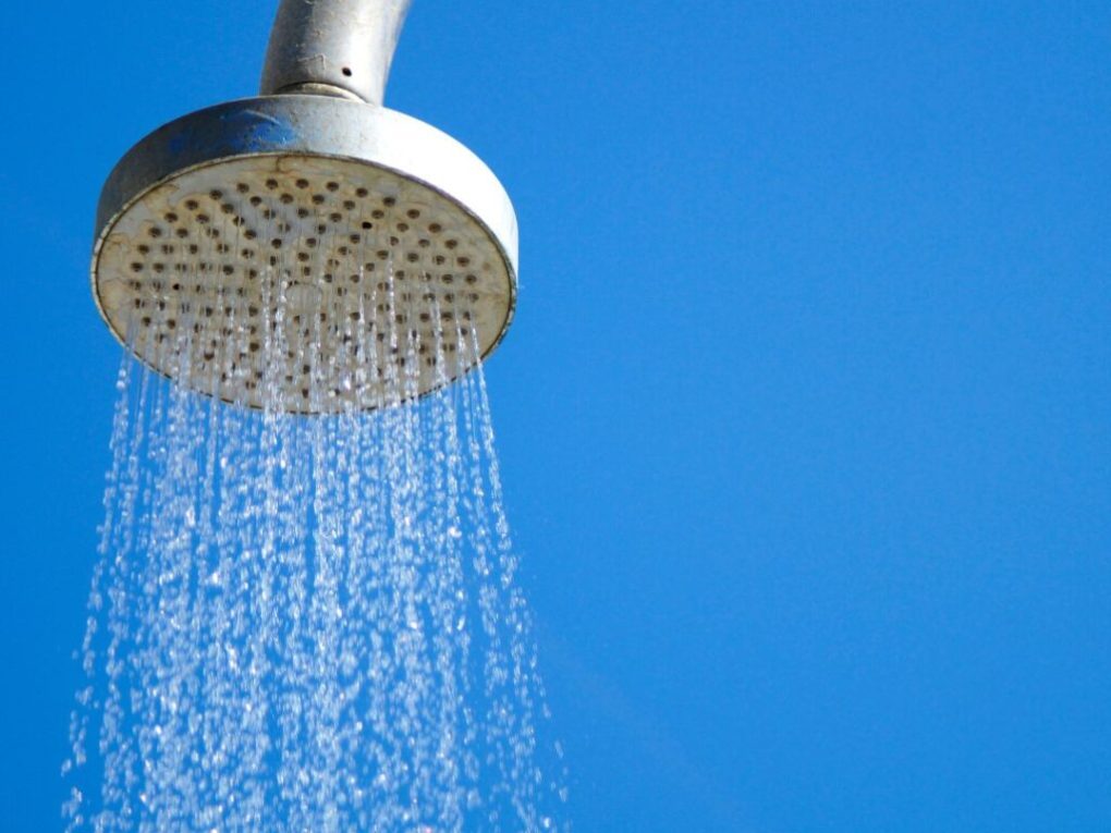 back-to-School-25-1024×1024 Showerhead with water flowing against a clear blue sky.